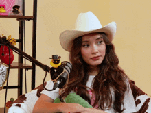 a woman wearing a white cowboy hat sitting in front of a microphone