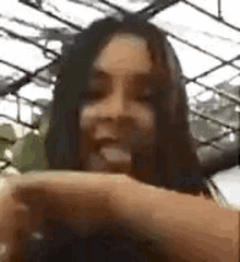 a close up of a woman 's face while holding a cell phone in a greenhouse .