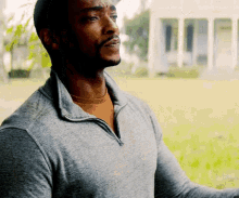 a man with a beard wearing a grey sweater and a brown shirt