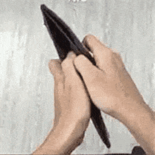 a person is holding an empty wallet in their hands against a wall .