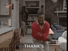 a man is dancing in a living room with the words `` thank 's '' written above him .