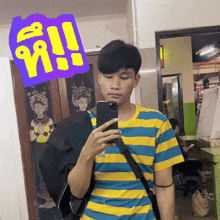 a man in a yellow and blue striped shirt taking a selfie