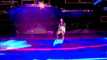 a woman is standing on a stage in front of a crowd with a purple background .