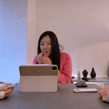 a woman sits at a table with a tablet that says ipad