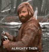 a man with a beard and long hair is holding a motorcycle .