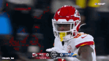 a football player wearing a red helmet stands in front of a scoreboard that says lac