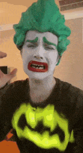 a man wearing a green wig and a batman shirt is crying