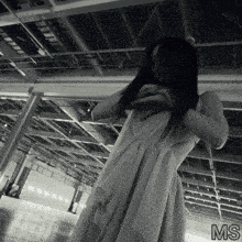 a woman in a white dress is standing in a dark room with the letters ms on the bottom