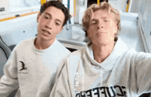two young men are posing for a picture and one of them has a tik tok sticker on his shirt