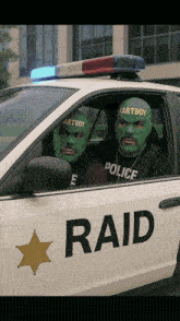 two men wearing green masks are sitting in a white police car that says raid