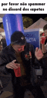 a man is drinking from a red cup while dancing in front of a blue inflatable balloon .