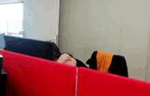 a woman is sitting in a cubicle with her head in her hands .