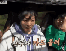 a group of people are sitting in a car with korean writing on the side .
