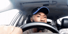a man is driving a car and wearing a hat with the letter c on it
