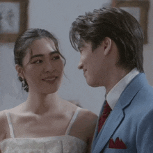 a man in a suit and a woman in a wedding dress are looking at each other