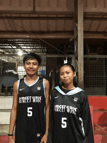 a boy and a girl are standing next to each other wearing street wise jerseys