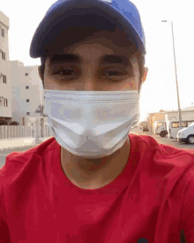 a man wearing a red shirt and a blue hat is wearing a face mask