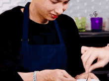 a man wearing a blue apron is cutting a piece of food