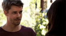 a man with a beard and a purple shirt is looking at a woman