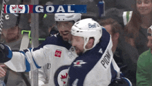 two hockey players are celebrating a goal with a banner that says goal on it