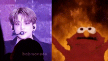 a man is singing in front of a crowd next to a picture of elmo on a screen .