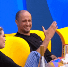 a man is sitting in a yellow chair with his hand in the air