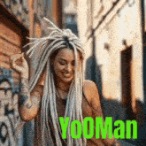 a woman with dreadlocks is smiling and dancing in front of a building in a city .