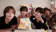 a group of young men are sitting around a table with a birthday cake in front of them