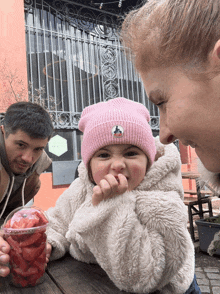 a little girl wearing a pink beanie with a boat logo on it