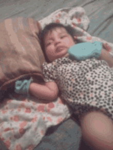 a baby is laying on a bed wearing a leopard print outfit and blue gloves