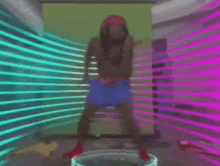 a man with dreadlocks is dancing in a room with neon lights behind him .