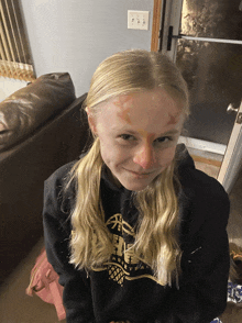 a girl wearing a black sweatshirt with a gold basketball on it