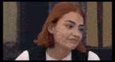 a young woman with red hair is making a funny face .