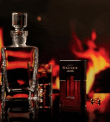 a bottle of avon black suede cologne sits next to a decanter