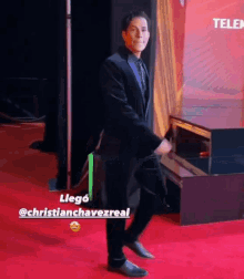 a man in a suit and tie is dancing on a red carpet ..