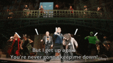 a group of people dancing on a stage with the words but i get up again you 're never gonna keep me down on the bottom