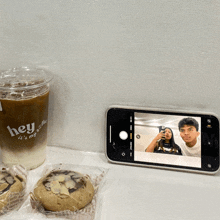 a phone taking a picture of a man and woman next to a cup that says hey