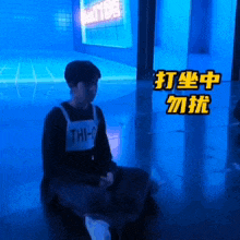 a person wearing a shirt that says " thi-0 " sits on the floor