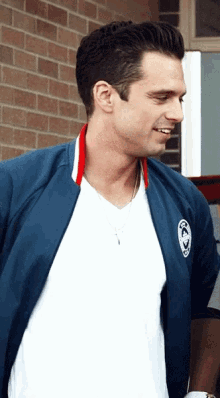 a man wearing a white t-shirt and a blue jacket with the letters cc on the sleeve