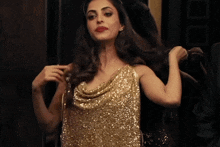 a woman in a gold dress holds her hair