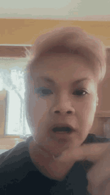 a woman with pink hair is making a funny face with her finger in her mouth