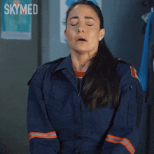 a woman with her eyes closed is wearing a blue uniform with the word skymed on it