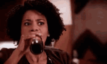 a woman is drinking a glass of wine from a glass .