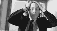 a man in a suit and tie is holding his head in a black and white photo .