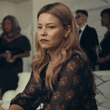 a woman in a floral shirt is sitting in a room