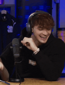 a man wearing headphones is laughing in front of a microphone that has the word prime on it