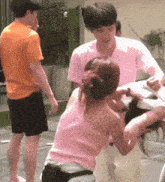 a woman in a pink tank top is standing next to a man in an orange shirt .