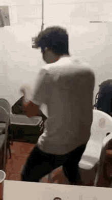 a man is dancing in a room in front of a table .
