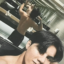 a shirtless man taking a selfie in front of a bathroom mirror