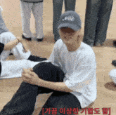 a man wearing a hat that says meo sits on the floor